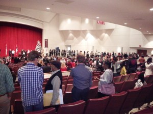 This shot was taken at the naturalization ceremony I attended, just after the ceremony concluded.  The man in the foreground (with the manila and white envelopes under his arm) is a new U.S. citizen, while in the background other new citizens are in line to have their photos taken with the judge.  On the far left, way in the back, between the U.S. and Texas flags, is the judge (in black) posing with a new citizen.