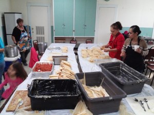During the tamalada, Mexican women are seen preparing tamales.  The tamales are the yellow-white items that look similar to burritos, while nearby vats contain different ingredients.